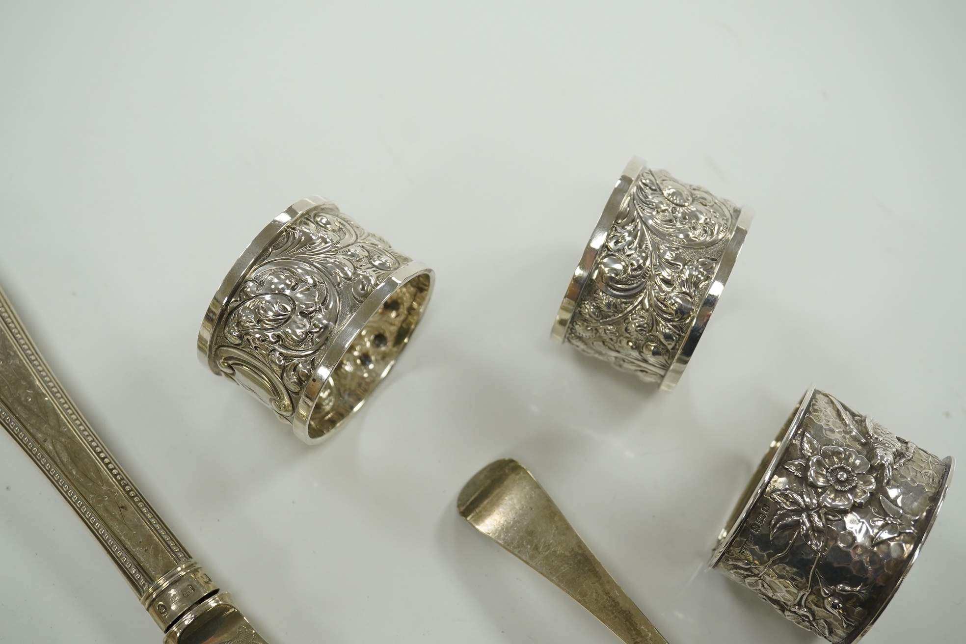 Small silver including a pair of napkin rings and two others, a Georgian sauce ladle and two similar dessert spoons, a fish slice, fork and an unmarked toddy ladle with inset coin bowl. Condition - poor to fair